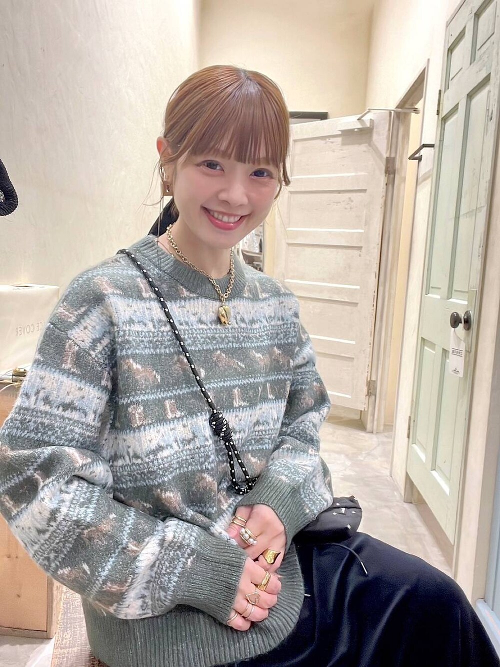 ブラック系のショルダーバッグ、ベージュ系のスリッポン、ブラック系のスカートを着用したレディースの冬コーディネートの3枚目の写真