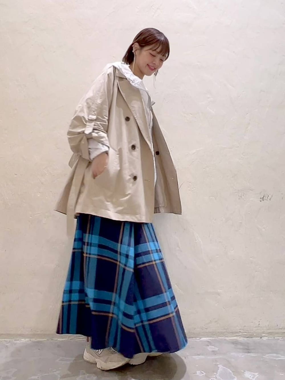 ベージュ系のトレンチコート、ベージュ系のキャミソール、ホワイト系のマウンテンパーカーを着用したレディースの春コーディネートの4枚目の写真