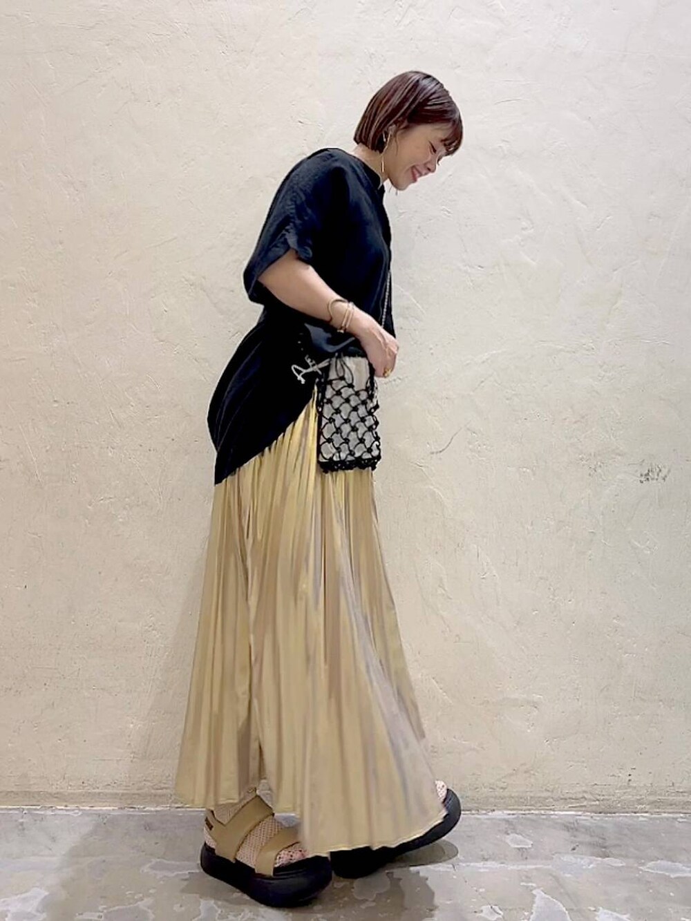 ブラック系のショルダーバッグ、イエロー系のサンダル、イエロー系のスカートを着用したレディースの夏コーディネートの2枚目の写真