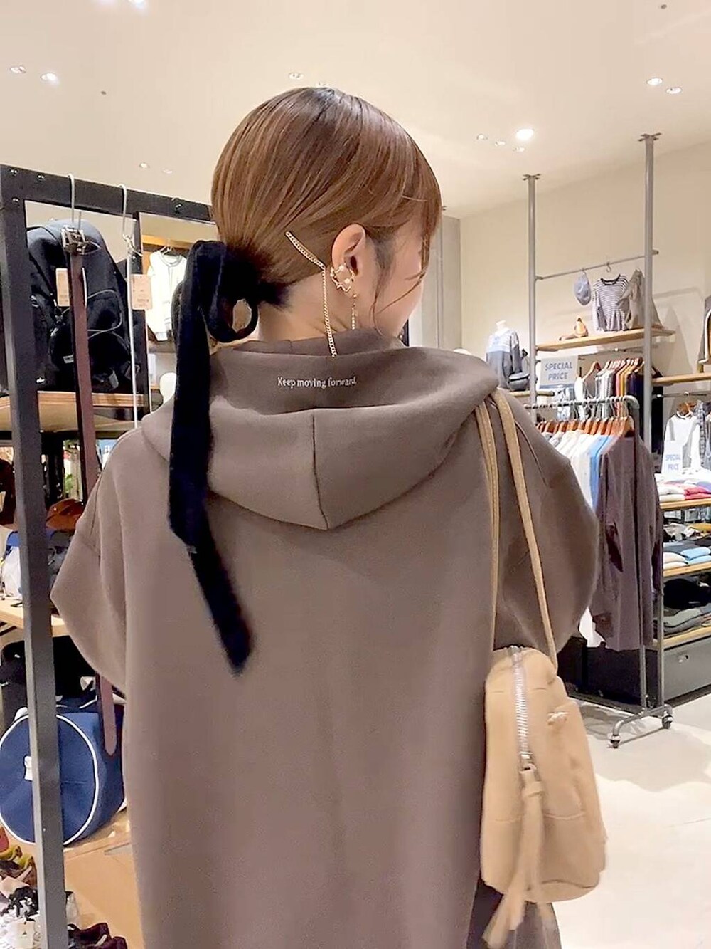 イエロー系のスカート、ブラウン系のパーカー、ベージュ系のボストンバッグを着用したレディースの秋コーディネートの3枚目の写真