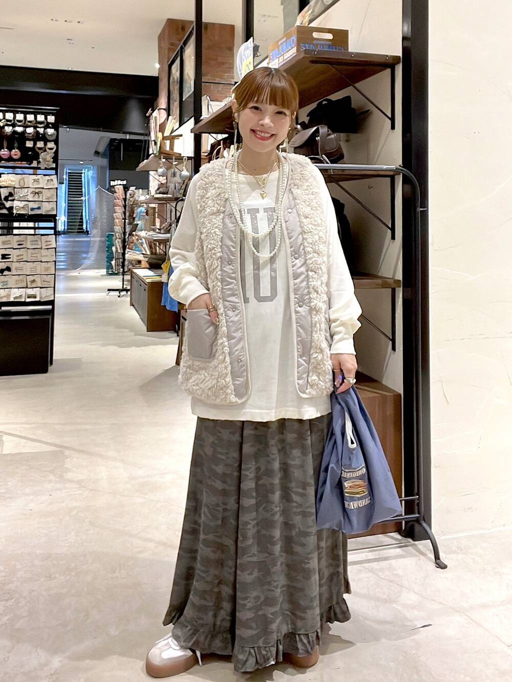 ベージュ系のベスト、その他のトートバッグ、グリーン系のスカートを着用したレディースの秋コーディネートの9枚目の写真