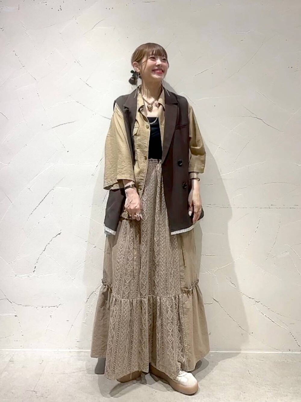 イエロー系のスカート、ブラウン系のベストを着用したレディースの夏コーディネートの3枚目の写真