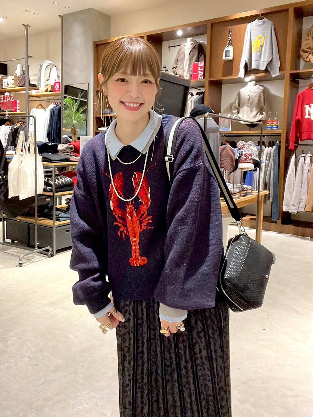 グレー系のスカート、ブラック系のショルダーバッグ、ベージュ系のスニーカーを着用したレディースの冬コーディネートの2枚目の写真
