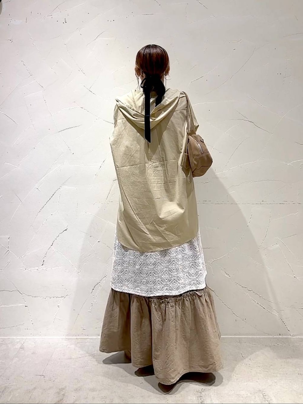 イエロー系のスカート、ベージュ系のボストンバッグ、ベージュ系のワンピースを着用したレディースの秋コーディネートの4枚目の写真