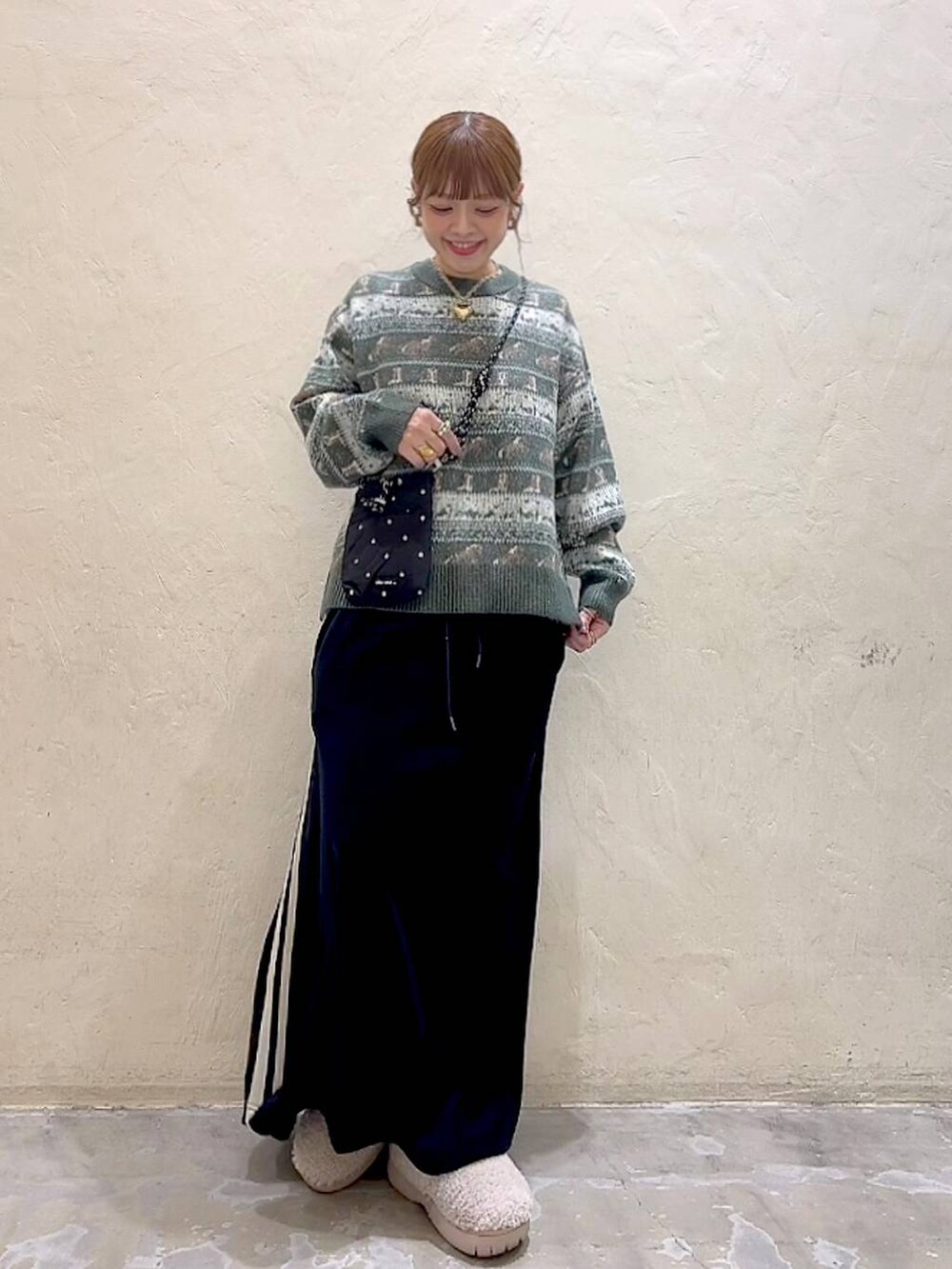 ブラック系のショルダーバッグ、ベージュ系のスリッポン、ブラック系のスカートを着用したレディースの冬コーディネートの4枚目の写真