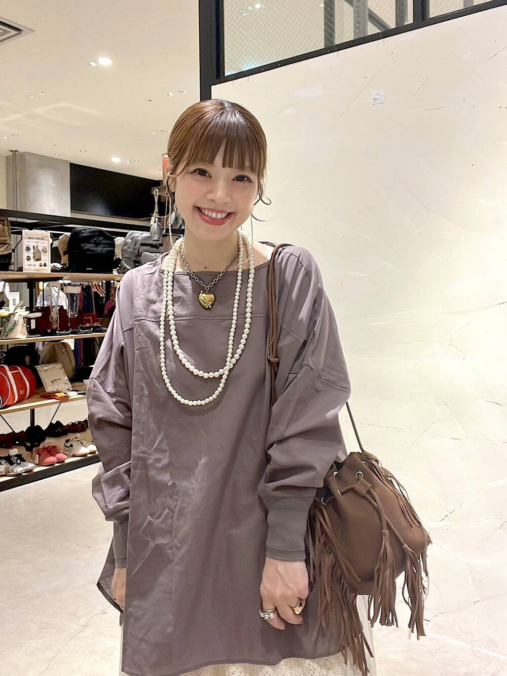 ベージュ系のスカート、ブラウン系のショルダーバッグ、ベージュ系のネックレスを着用したレディースの夏コーディネートの8枚目の写真