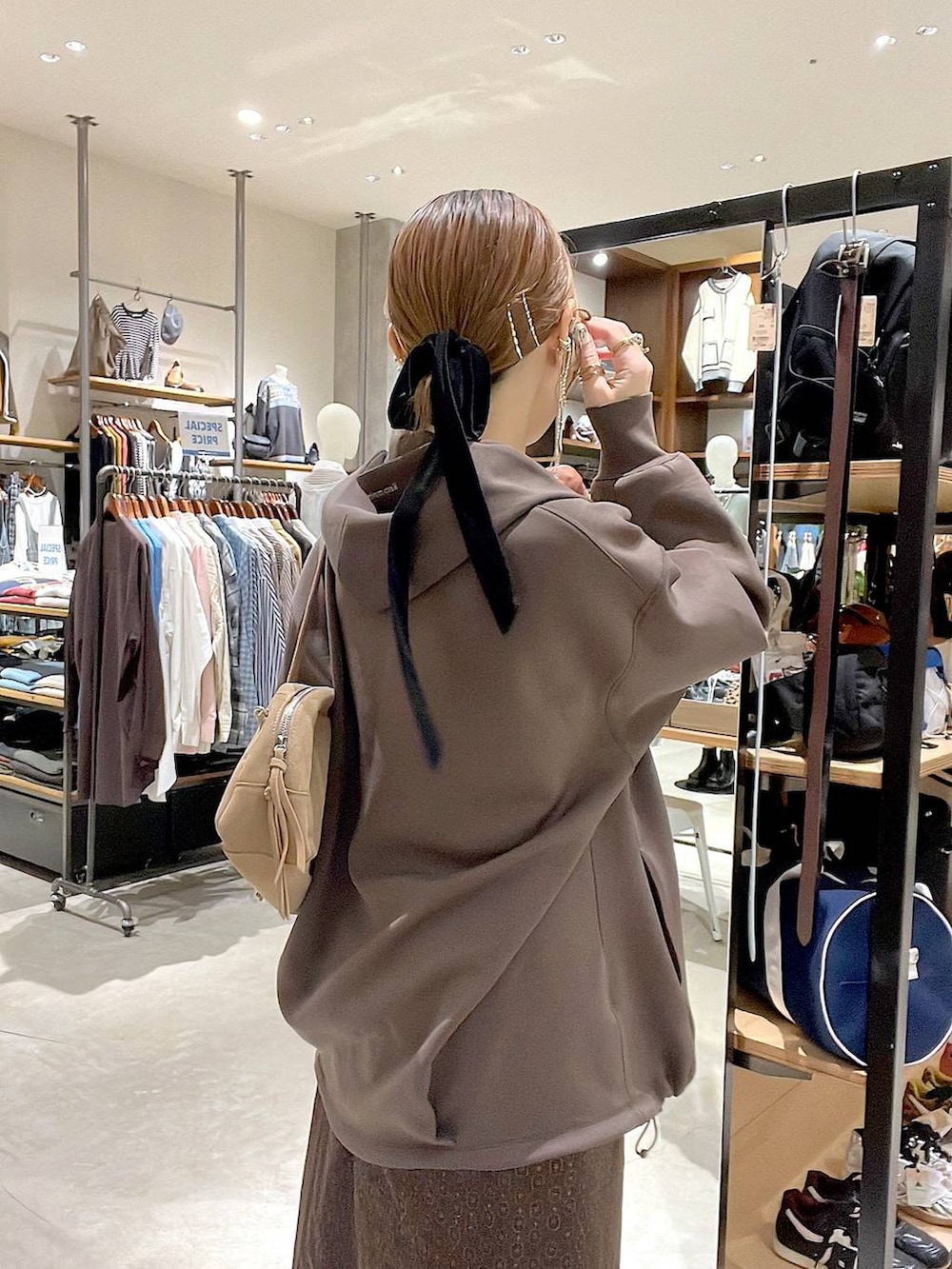 イエロー系のスカート、ブラウン系のパーカー、ベージュ系のボストンバッグを着用したレディースの秋コーディネートの6枚目の写真