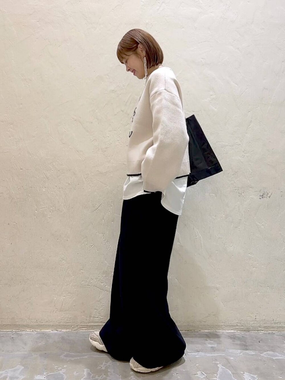 ホワイト系のTシャツ/カットソー、ブラック系のその他パンツ、ベージュ系のニット/セーターを着用したレディースの冬コーディネートの5枚目の写真