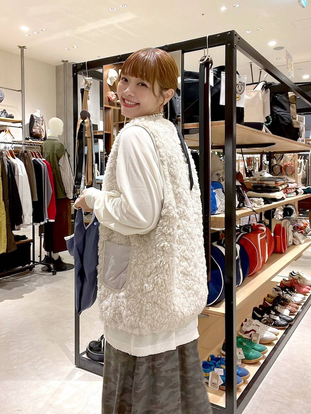 ベージュ系のベスト、その他のトートバッグ、グリーン系のスカートを着用したレディースの秋コーディネートの2枚目の写真