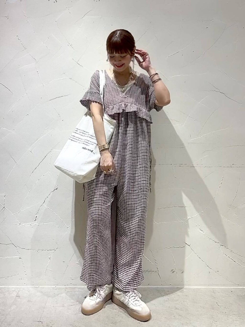 ベージュ系のトートバッグ、イエロー系のアナログ腕時計、ゴールド系のネックレスを着用したレディースの春コーディネートの3枚目の写真