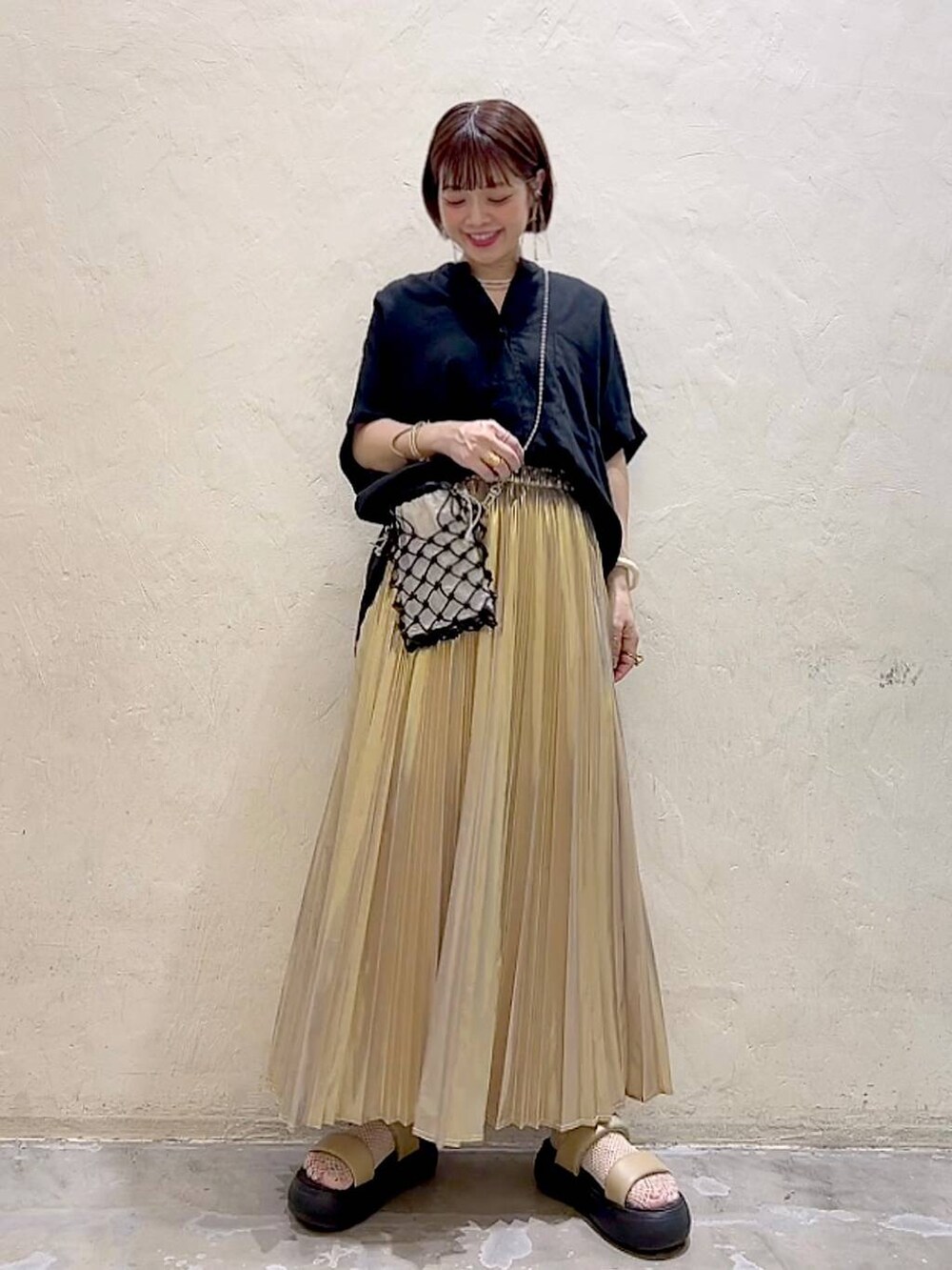 ブラック系のショルダーバッグ、イエロー系のサンダル、イエロー系のスカートを着用したレディースの夏コーディネートの5枚目の写真