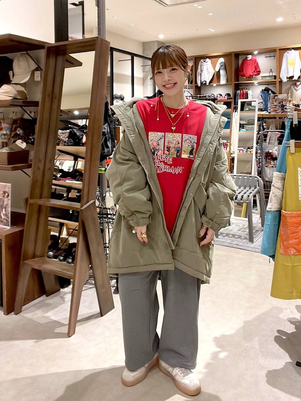 グリーン系のブルゾン、グレー系のその他パンツ、レッド系のスウェットを着用したレディースの冬コーディネートの3枚目の写真