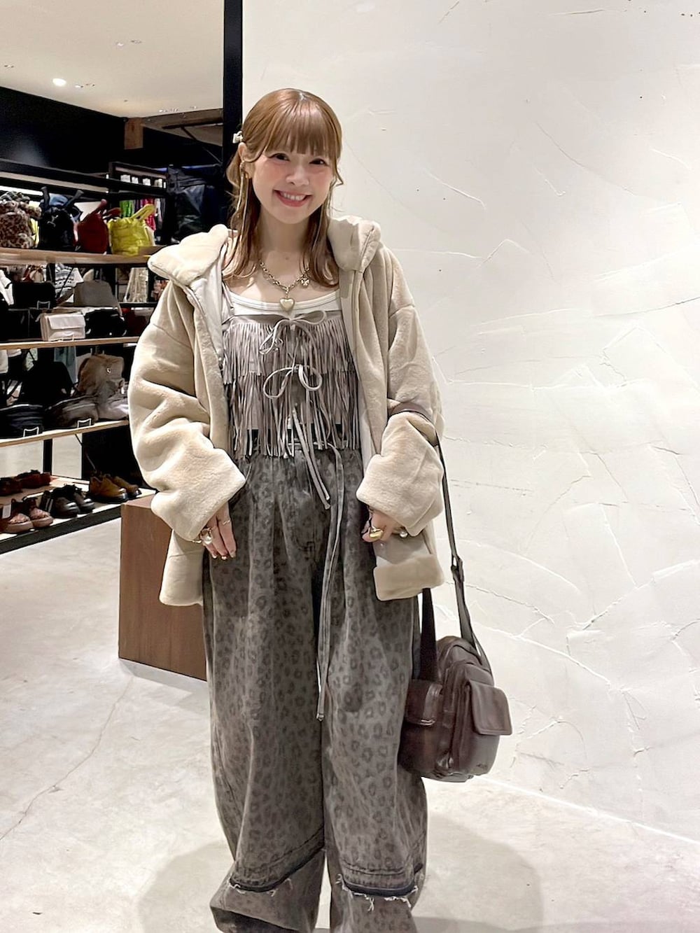 ブラウン系のデニムパンツ、ベージュ系のブルゾン、ブラウン系のショルダーバッグを着用したレディースの冬コーディネートの2枚目の写真