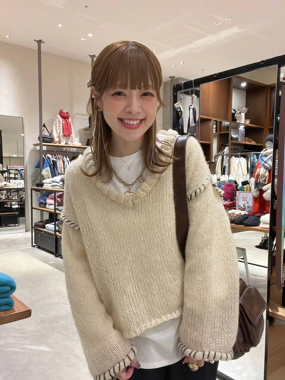 ホワイト系のTシャツ/カットソー、ブラウン系のショルダーバッグ、ベージュ系のスニーカーを着用したレディースの冬コーディネートの3枚目の写真