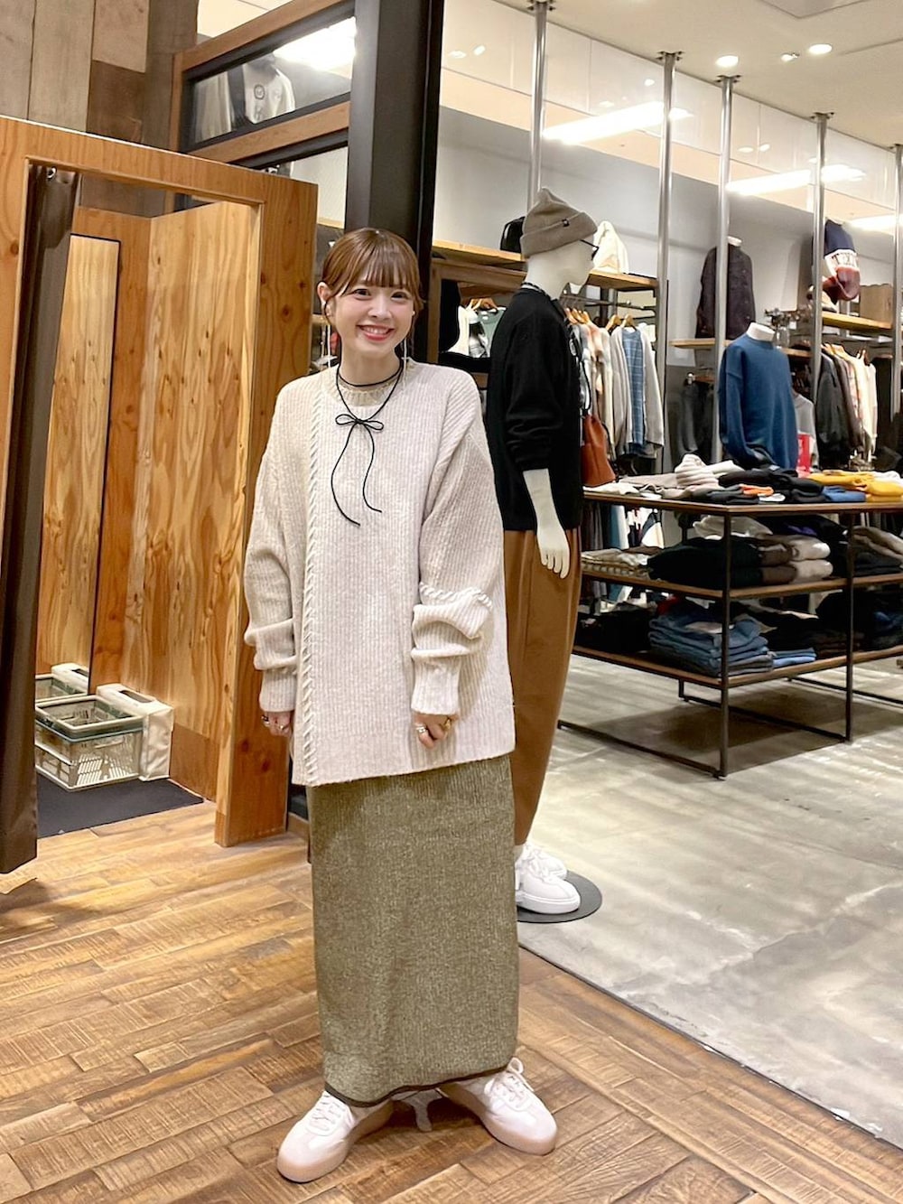 イエロー系のスカート、ベージュ系のニット/セーター、ブラック系のチョーカーを着用したレディースの秋コーディネートの7枚目の写真