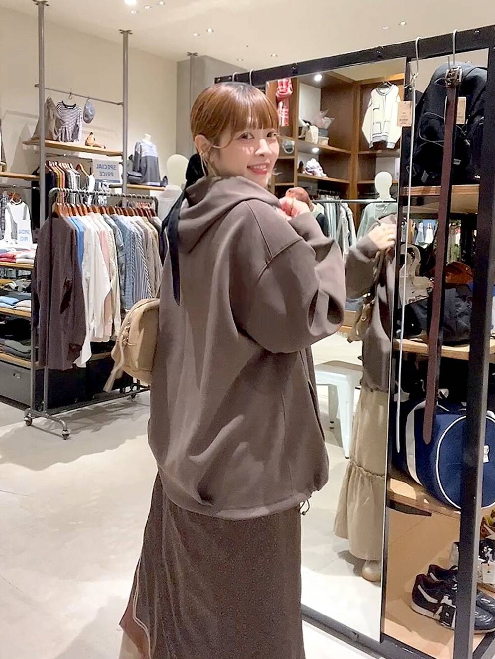 イエロー系のスカート、ブラウン系のパーカー、ベージュ系のボストンバッグを着用したレディースの秋コーディネートの5枚目の写真