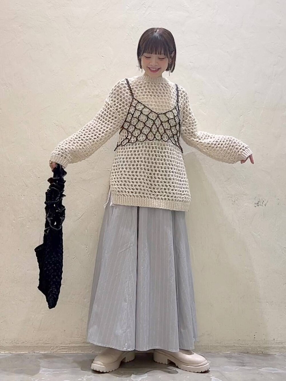 ブラック系のベスト、ベージュ系のブーツ、ブラック系のトートバッグを着用したレディースの冬コーディネートの6枚目の写真