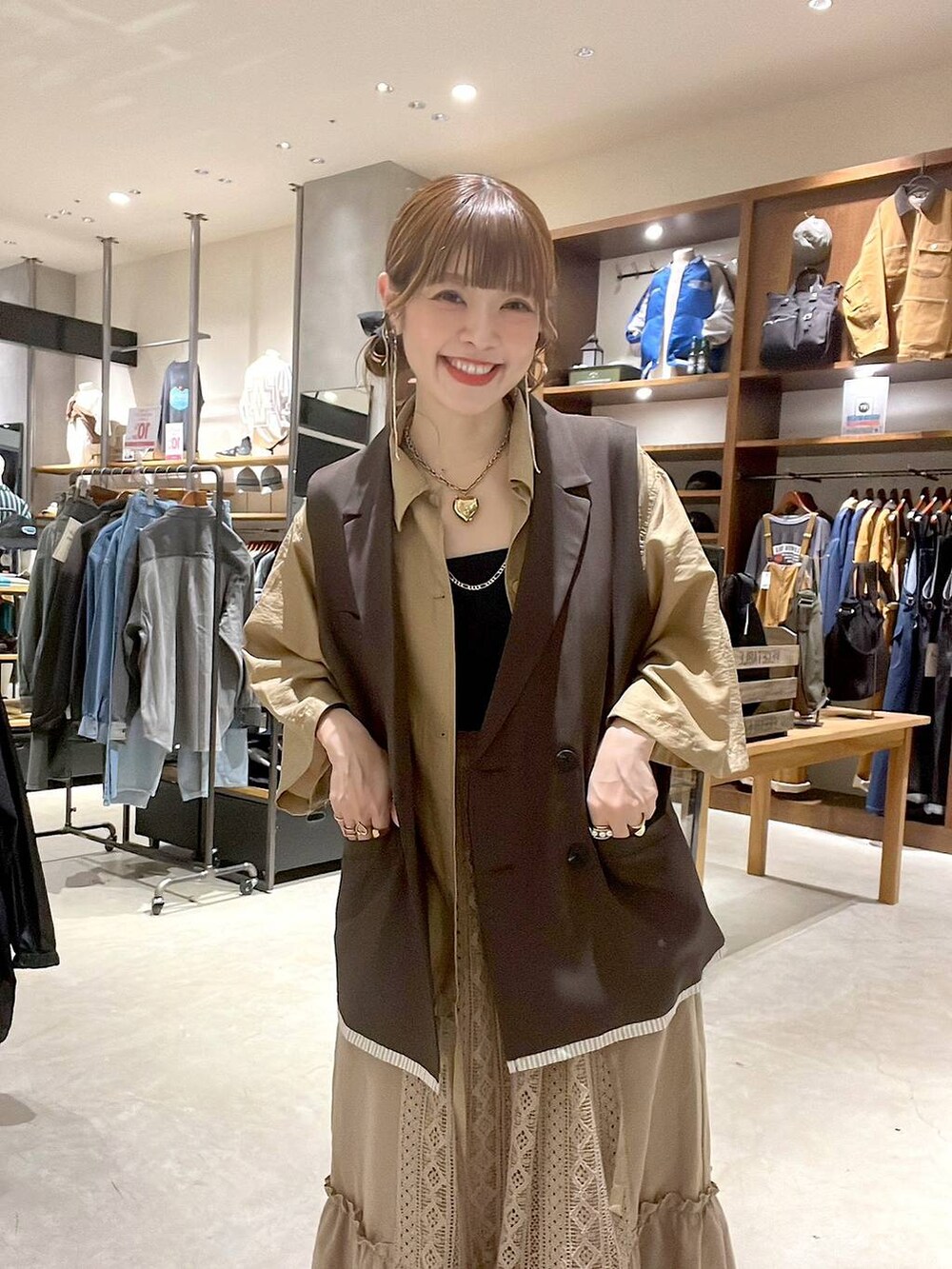 イエロー系のスカート、ブラウン系のベストを着用したレディースの夏コーディネートの2枚目の写真