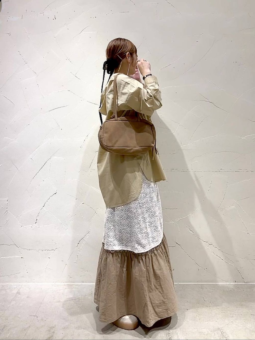 イエロー系のスカート、ベージュ系のボストンバッグ、ベージュ系のワンピースを着用したレディースの秋コーディネートの3枚目の写真