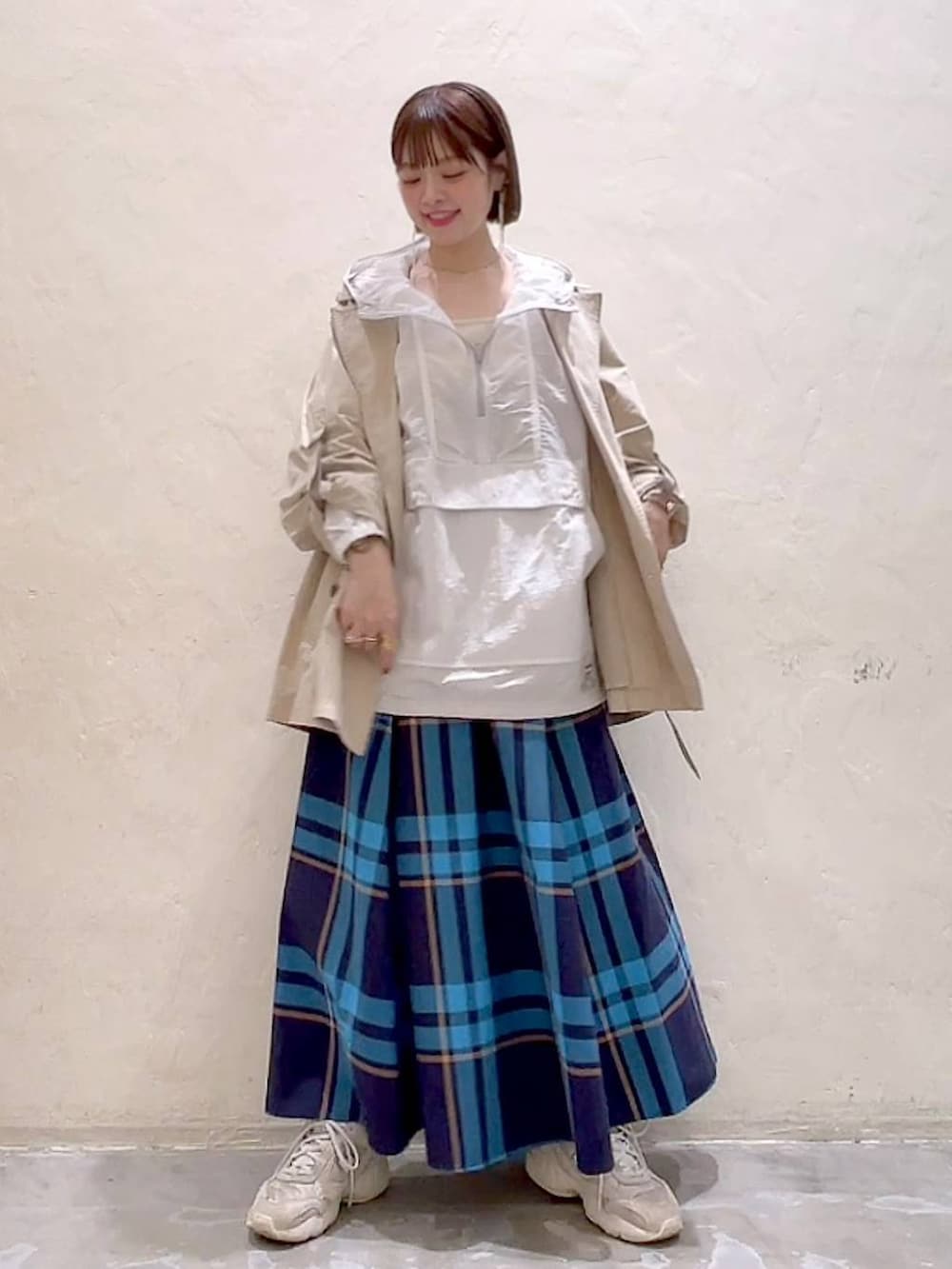 ベージュ系のトレンチコート、ベージュ系のキャミソール、ホワイト系のマウンテンパーカーを着用したレディースの春コーディネートの7枚目の写真