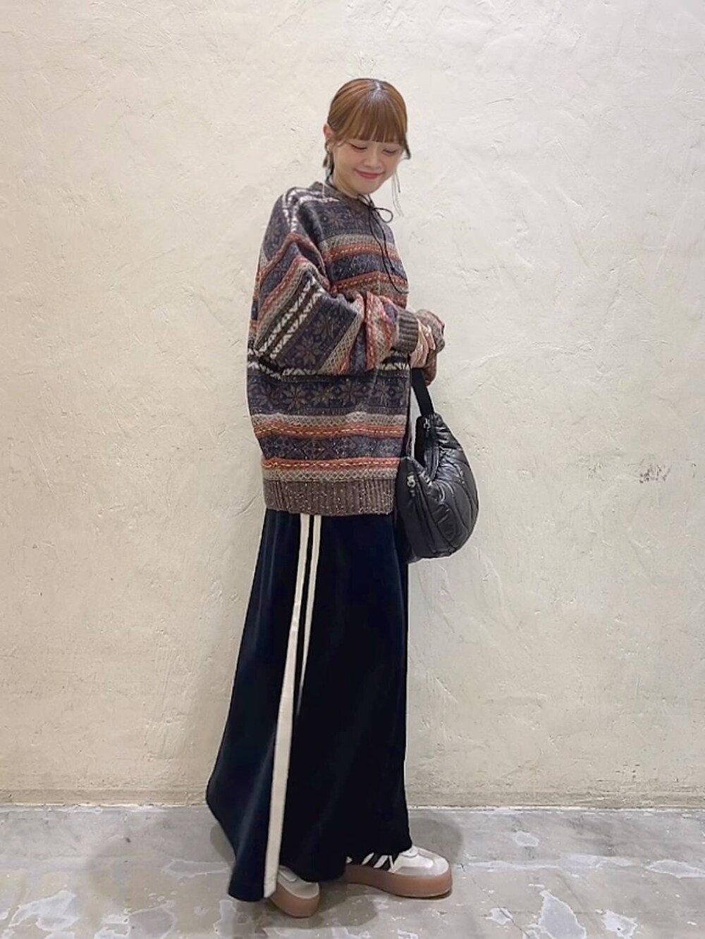 ブラック系のショルダーバッグ、ブラウン系のニット/セーター、ブラック系のスカートを着用したレディースの冬コーディネートの2枚目の写真