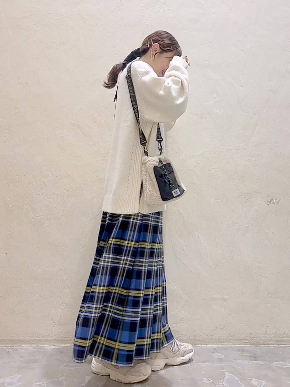 ブルー系のスカート、ホワイト系のニット/セーター、ベージュ系のショルダーバッグを着用したレディースの冬コーディネートの3枚目の写真