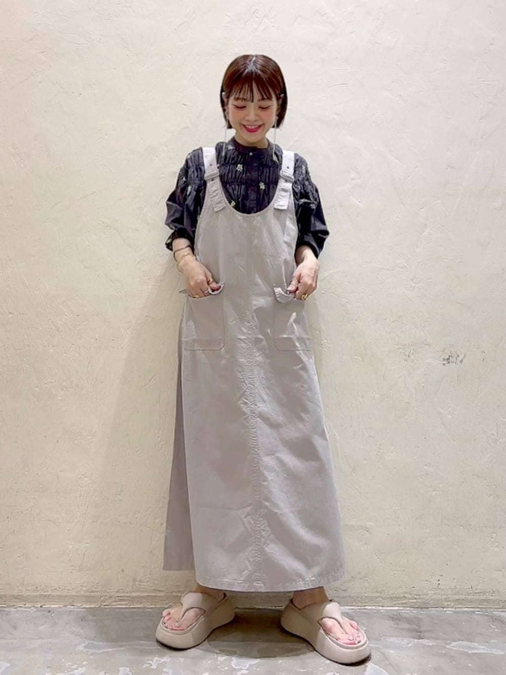 ベージュ系のサンダル、ブラック系のシャツ/ブラウス、グレー系のジャンパースカートを着用したレディースの春コーディネートの2枚目の写真