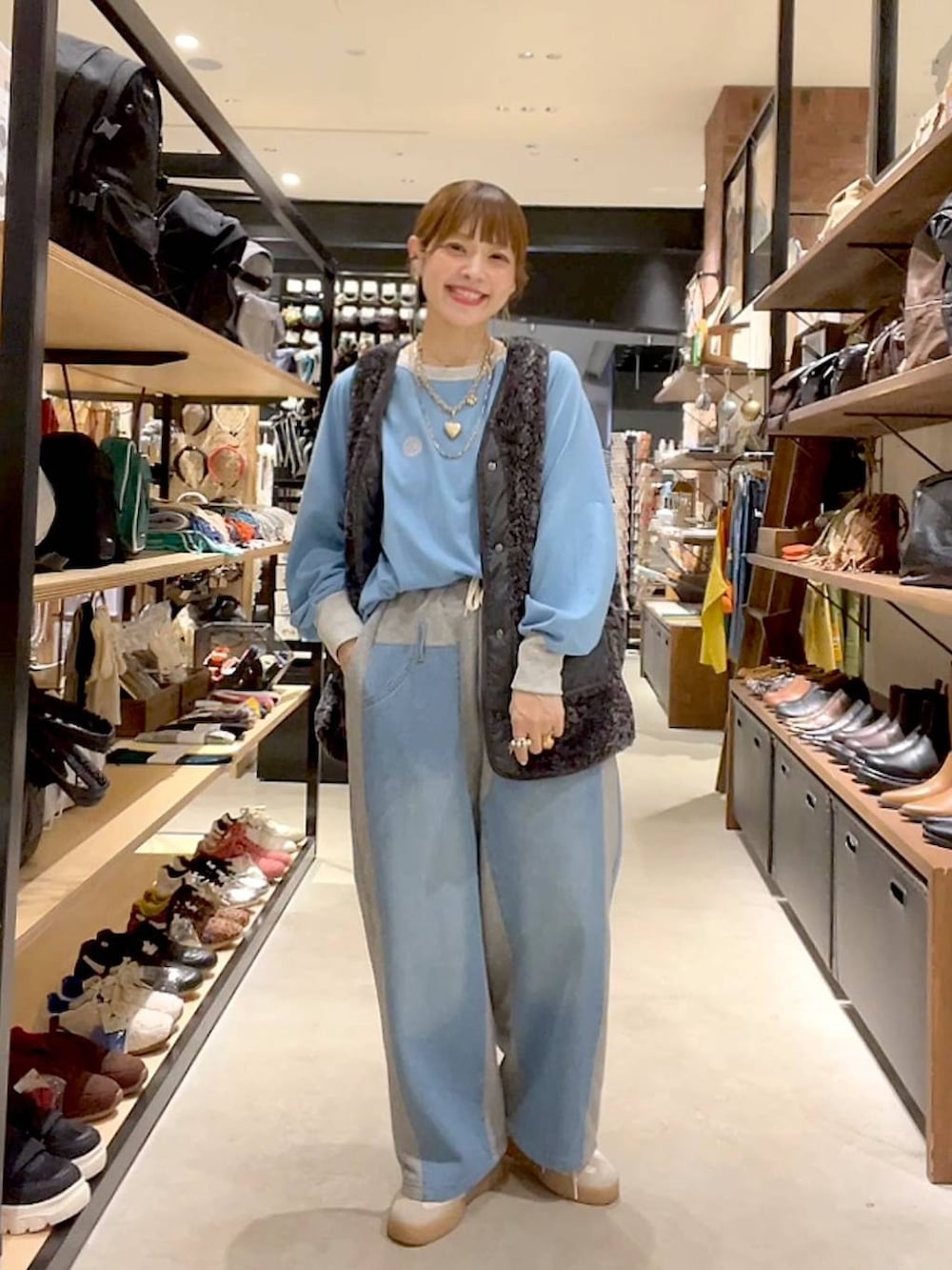 グレー系のベスト、グレー系のデニムパンツ、ゴールド系のネックレスを着用したレディースの秋コーディネートの6枚目の写真