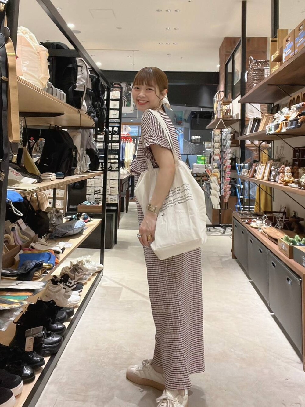 ベージュ系のトートバッグ、イエロー系のアナログ腕時計、ゴールド系のネックレスを着用したレディースの春コーディネートの2枚目の写真