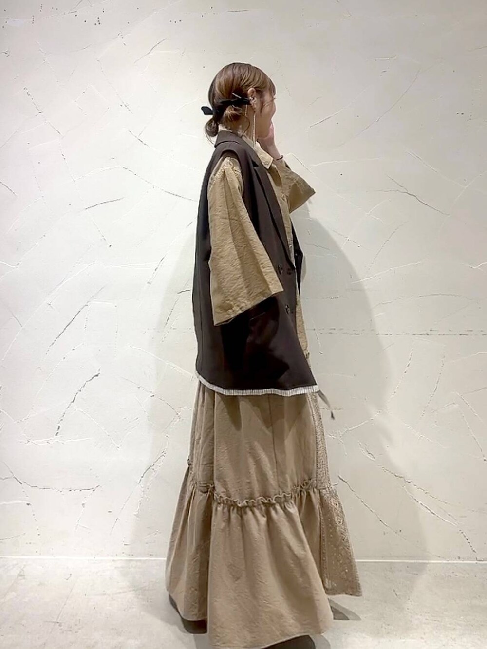 イエロー系のスカート、ブラウン系のベストを着用したレディースの夏コーディネートの6枚目の写真