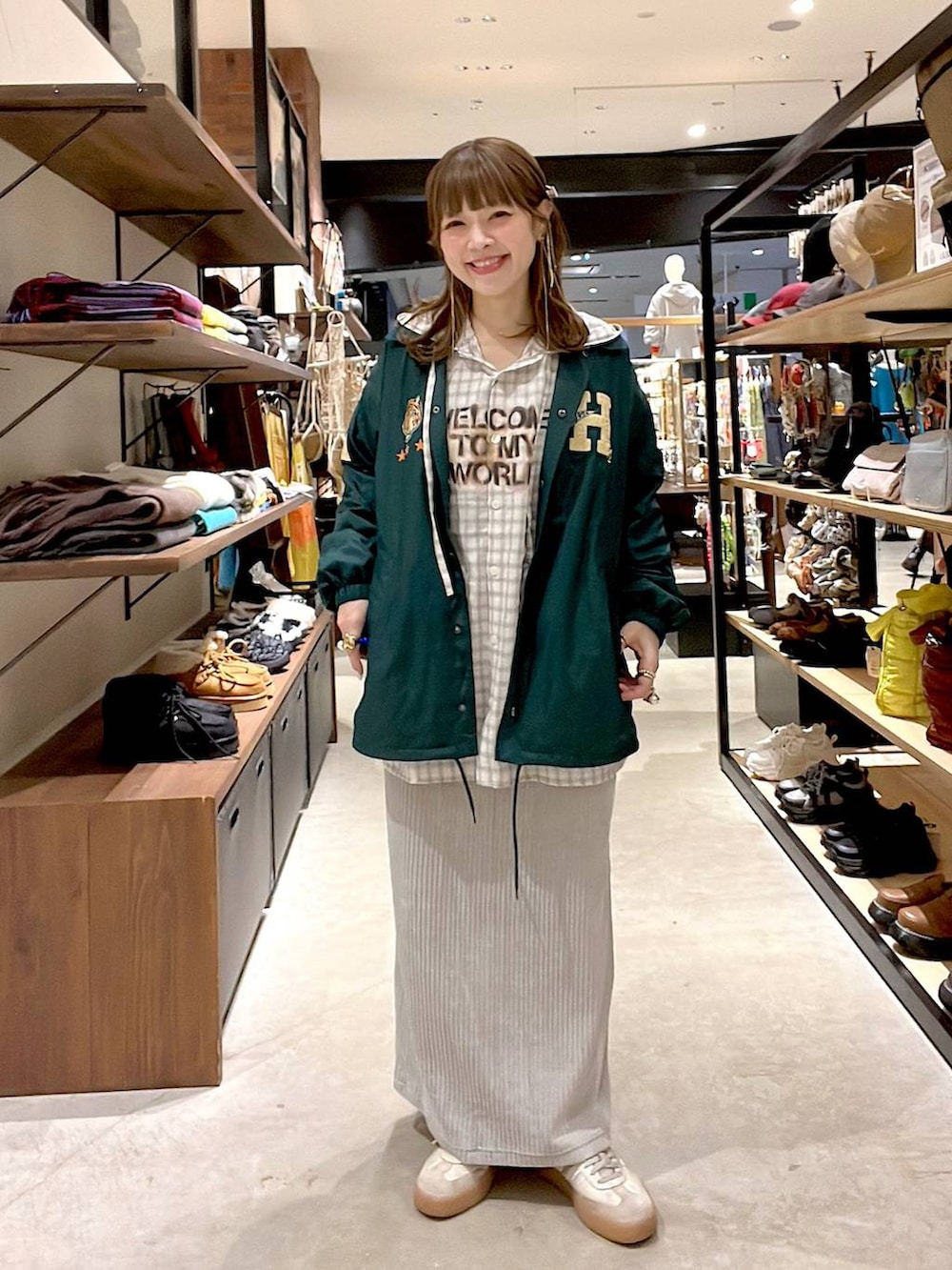 グレー系のスカート、ベージュ系のシャツ/ブラウス、グリーン系のナイロンジャケットを着用したレディースの冬コーディネートの2枚目の写真