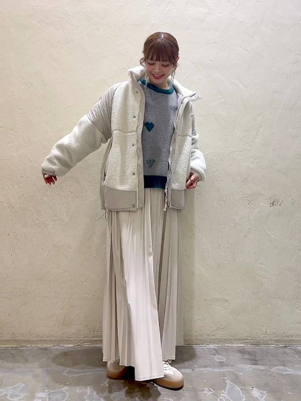 ベージュ系のスカート、ベージュ系のブルゾン、グレー系のニット/セーターを着用したレディースの秋コーディネートの2枚目の写真