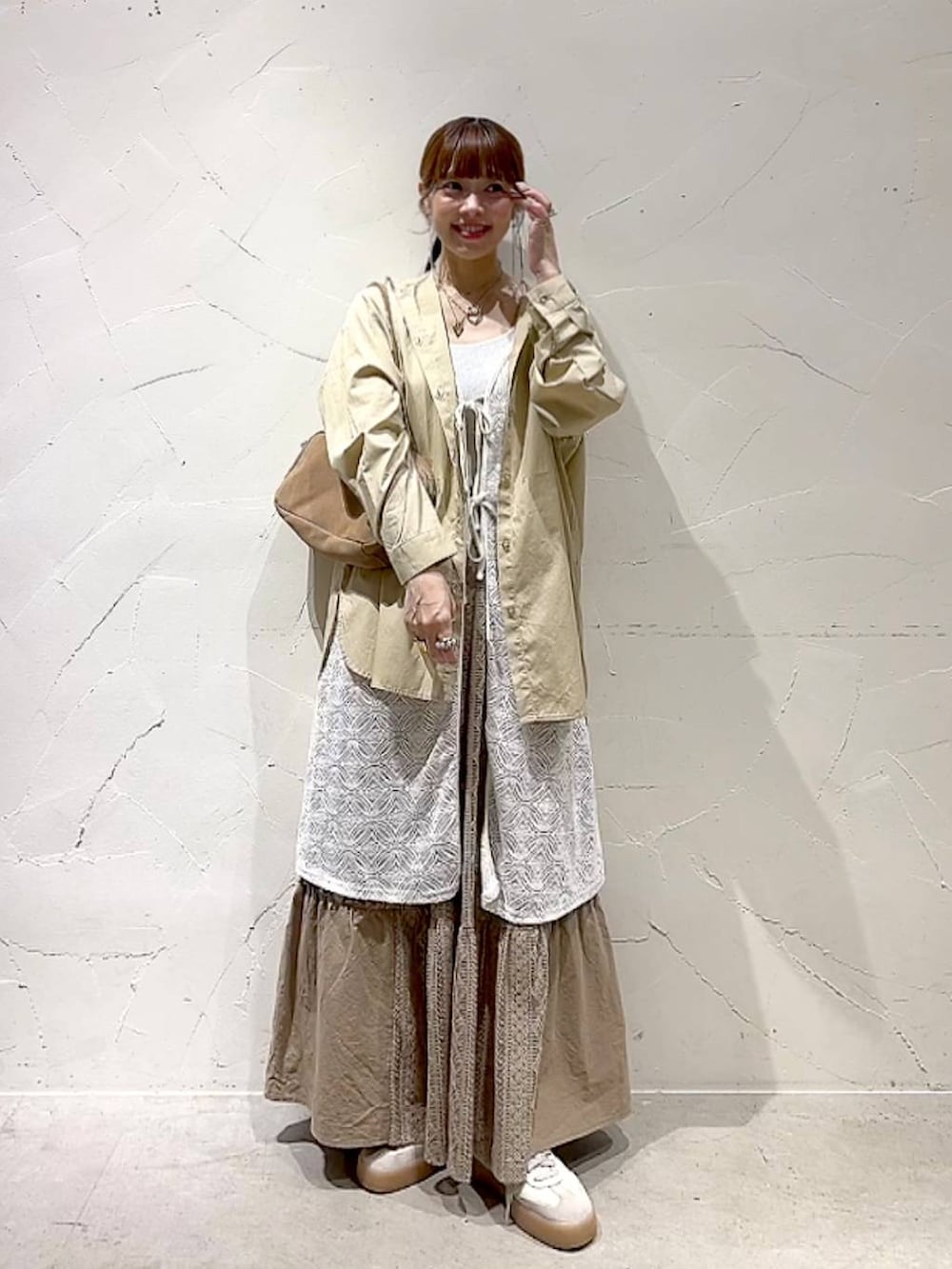 イエロー系のスカート、ベージュ系のボストンバッグ、ベージュ系のワンピースを着用したレディースの秋コーディネートの2枚目の写真