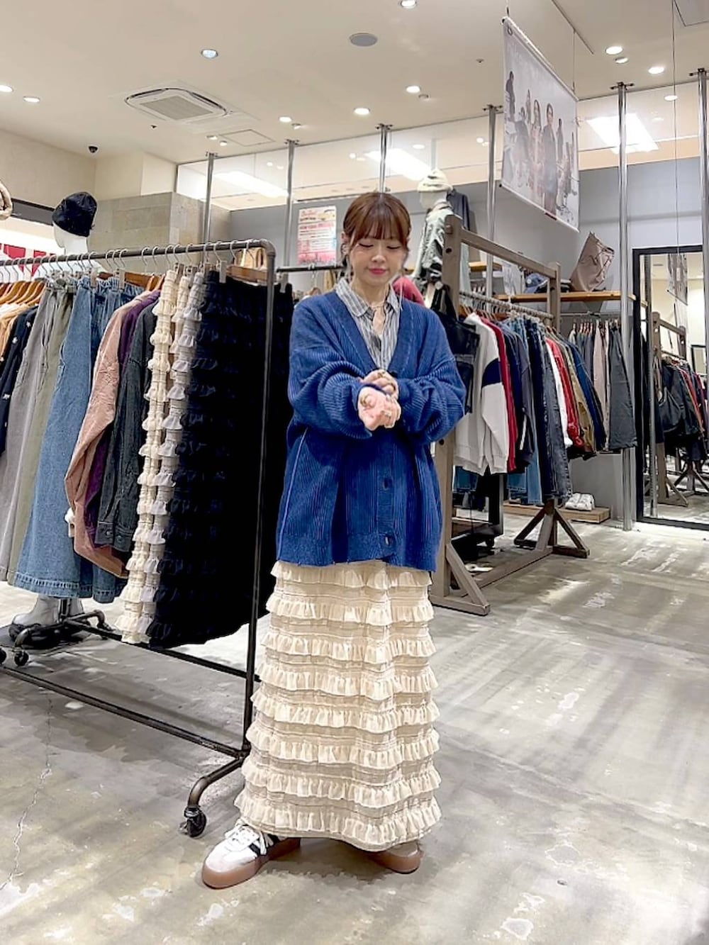 グレー系のシャツ/ブラウス、ベージュ系のスカート、ブルー系のカーディガン/ボレロを着用したレディースの秋コーディネートの2枚目の写真