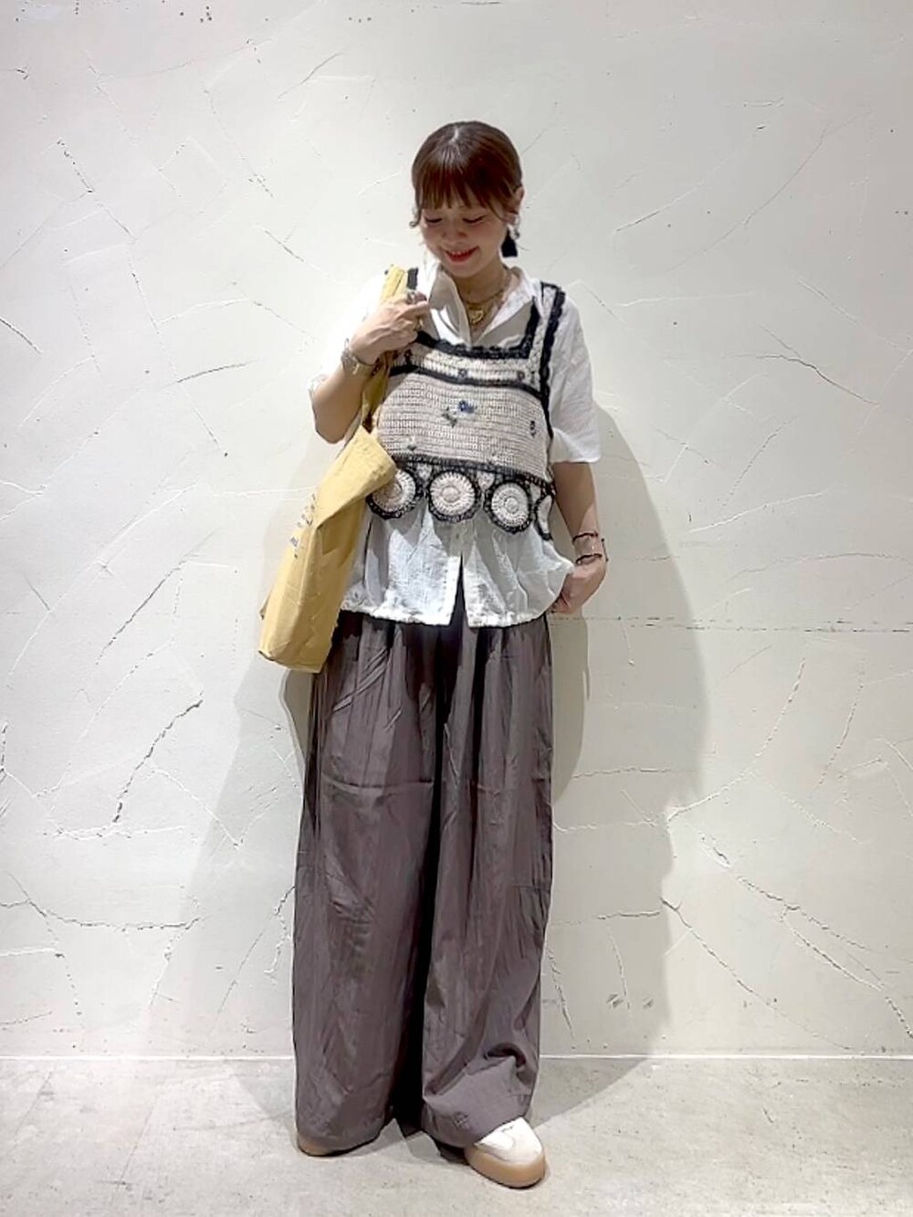 イエロー系のトートバッグ、ホワイト系のキャミソール、ホワイト系のシャツ/ブラウスを着用したレディースの夏コーディネートの3枚目の写真