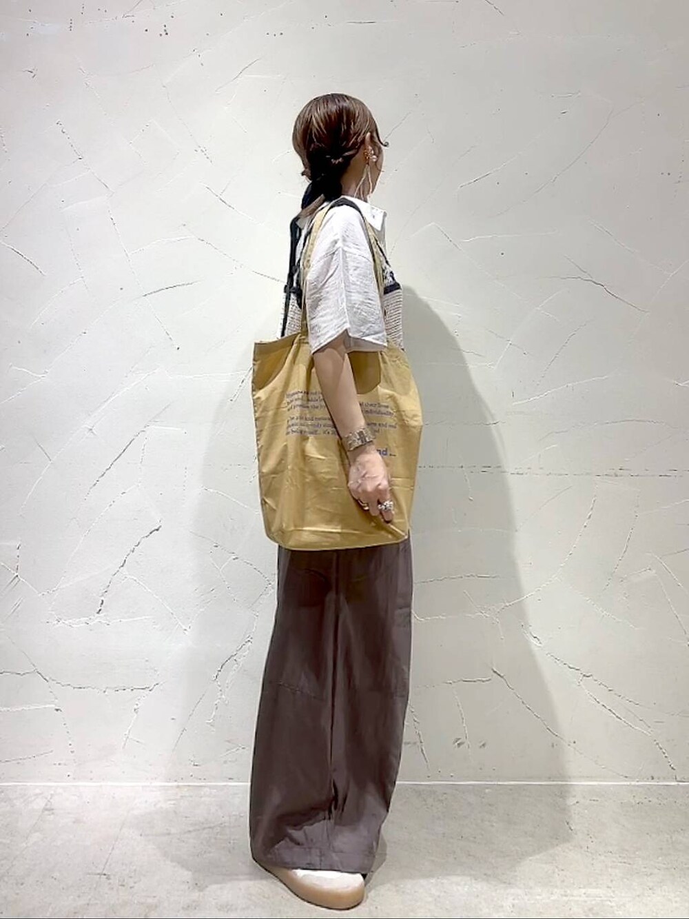 イエロー系のトートバッグ、ホワイト系のキャミソール、ホワイト系のシャツ/ブラウスを着用したレディースの夏コーディネートの4枚目の写真