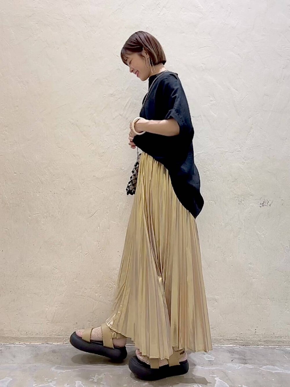 ブラック系のショルダーバッグ、イエロー系のサンダル、イエロー系のスカートを着用したレディースの夏コーディネートの4枚目の写真