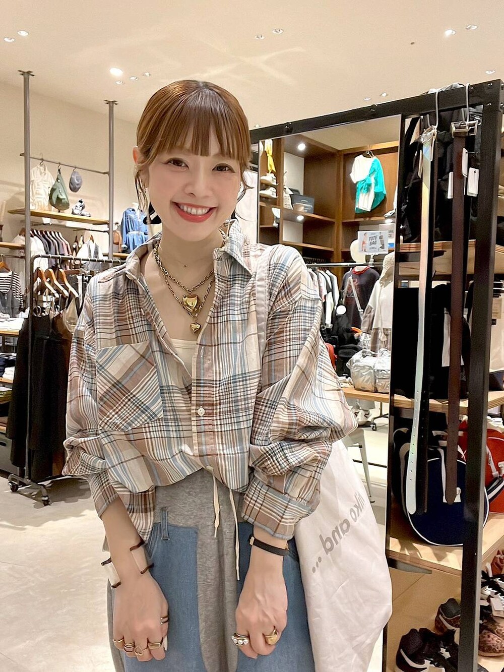 ベージュ系のシャツ/ブラウス、グレー系のトートバッグ、グレー系のデニムパンツを着用したレディースの夏コーディネートの7枚目の写真