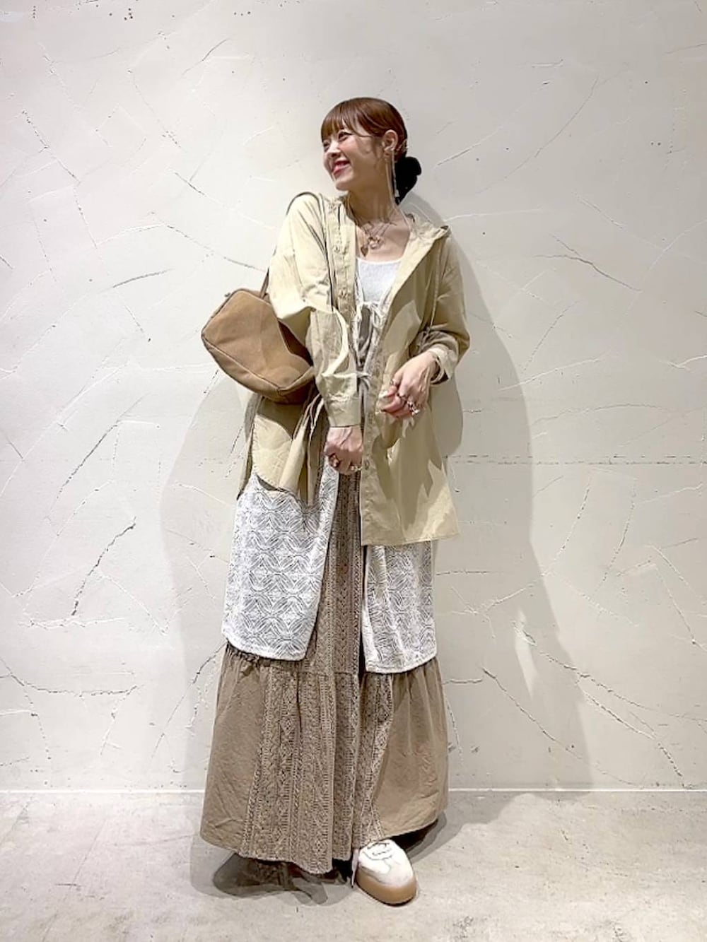 イエロー系のスカート、ベージュ系のボストンバッグ、ベージュ系のワンピースを着用したレディースの秋コーディネートの9枚目の写真