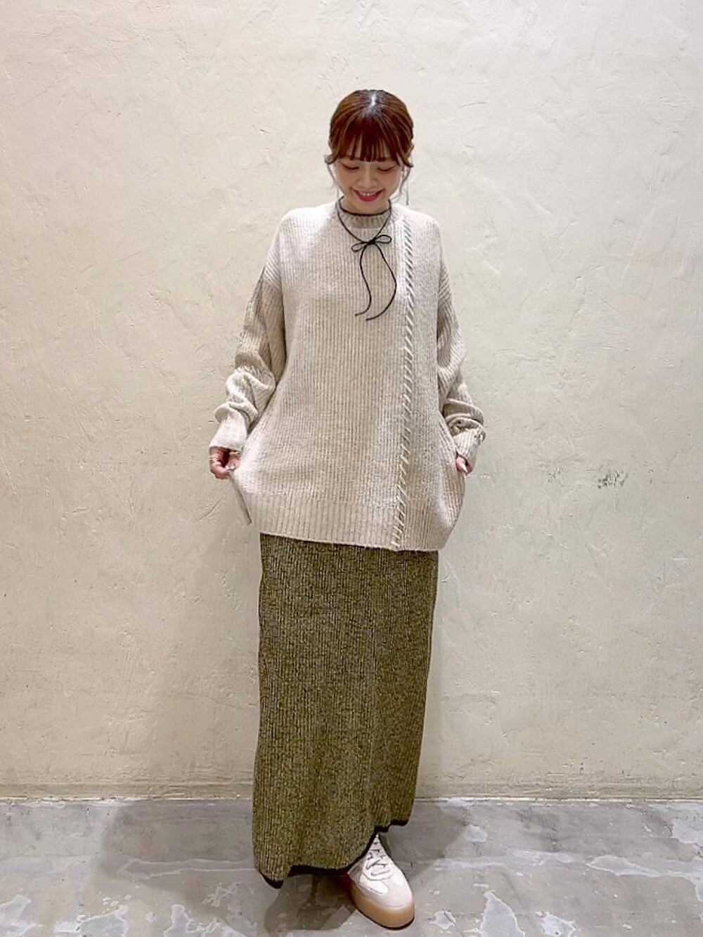 イエロー系のスカート、ベージュ系のニット/セーター、ブラック系のチョーカーを着用したレディースの秋コーディネートの2枚目の写真