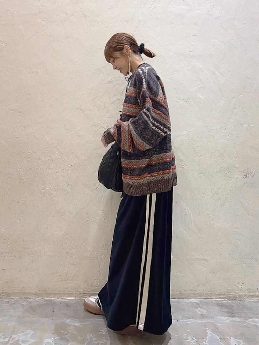 ブラック系のショルダーバッグ、ブラウン系のニット/セーター、ブラック系のスカートを着用したレディースの冬コーディネートの5枚目の写真