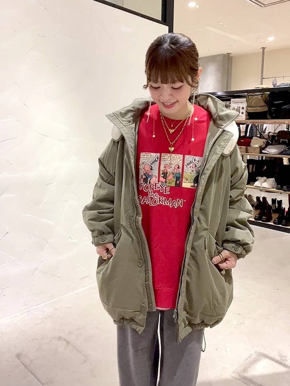 グリーン系のブルゾン、グレー系のその他パンツ、レッド系のスウェットを着用したレディースの冬コーディネートの4枚目の写真