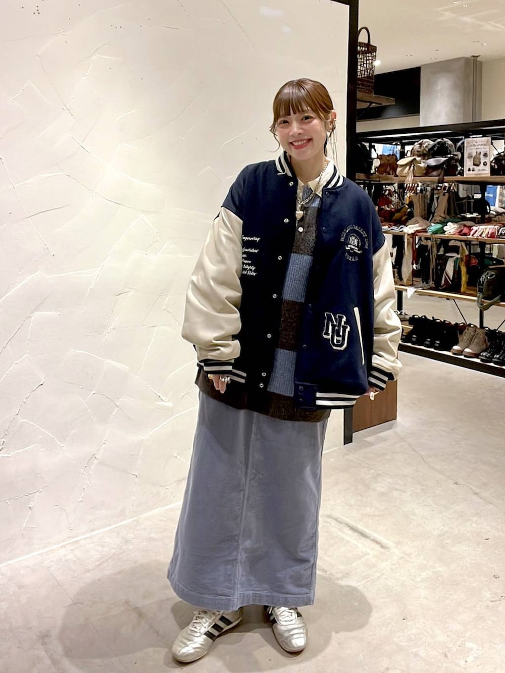 ゴールド系のスニーカー、ブルー系のスカート、ブルー系のブルゾンを着用したレディースの秋コーディネートの2枚目の写真