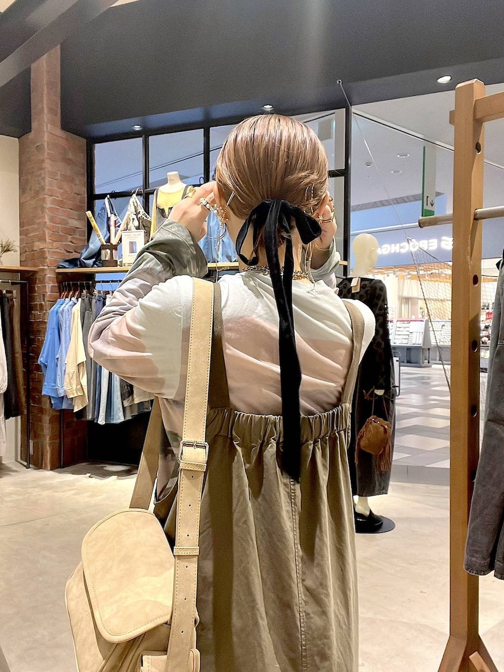 ベージュ系のTシャツ/カットソー、ベージュ系のショルダーバッグ、グリーン系のジャンパースカートを着用したレディースの夏コーディネートの4枚目の写真