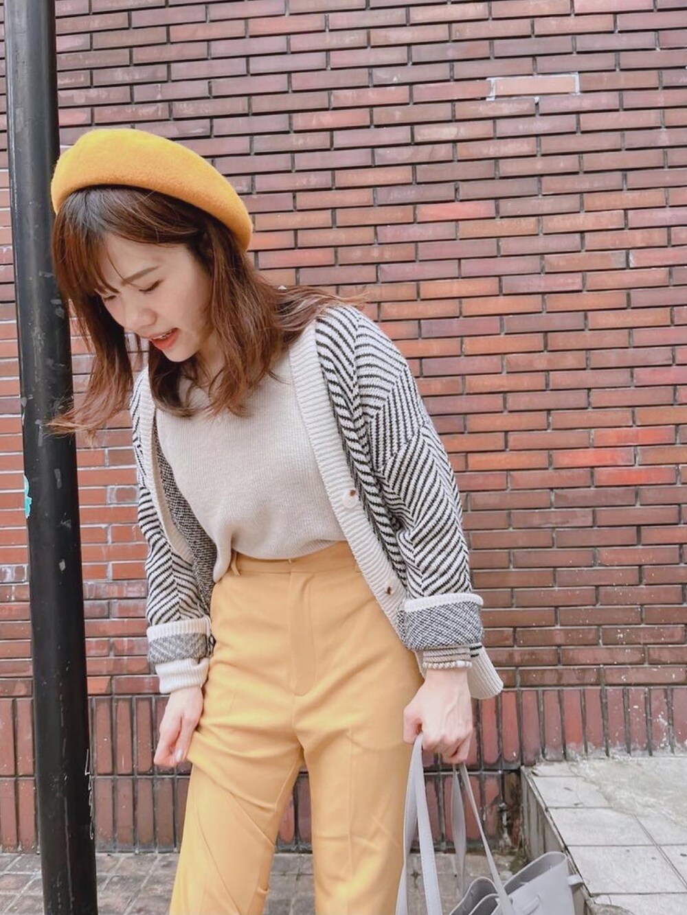 イエロー系のチノパンツ、ベージュ系のその他トップス、グレー系のトートバッグを着用したレディースの冬コーディネートの3枚目の写真