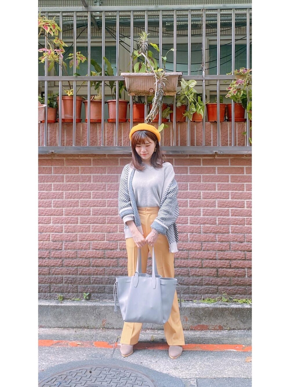 イエロー系のチノパンツ、ベージュ系のその他トップス、グレー系のトートバッグを着用したレディースの冬コーディネートの4枚目の写真