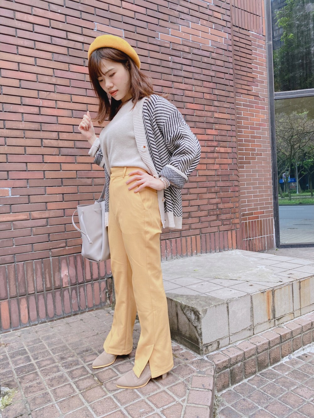 イエロー系のチノパンツ、ベージュ系のその他トップス、グレー系のトートバッグを着用したレディースの冬コーディネートの2枚目の写真
