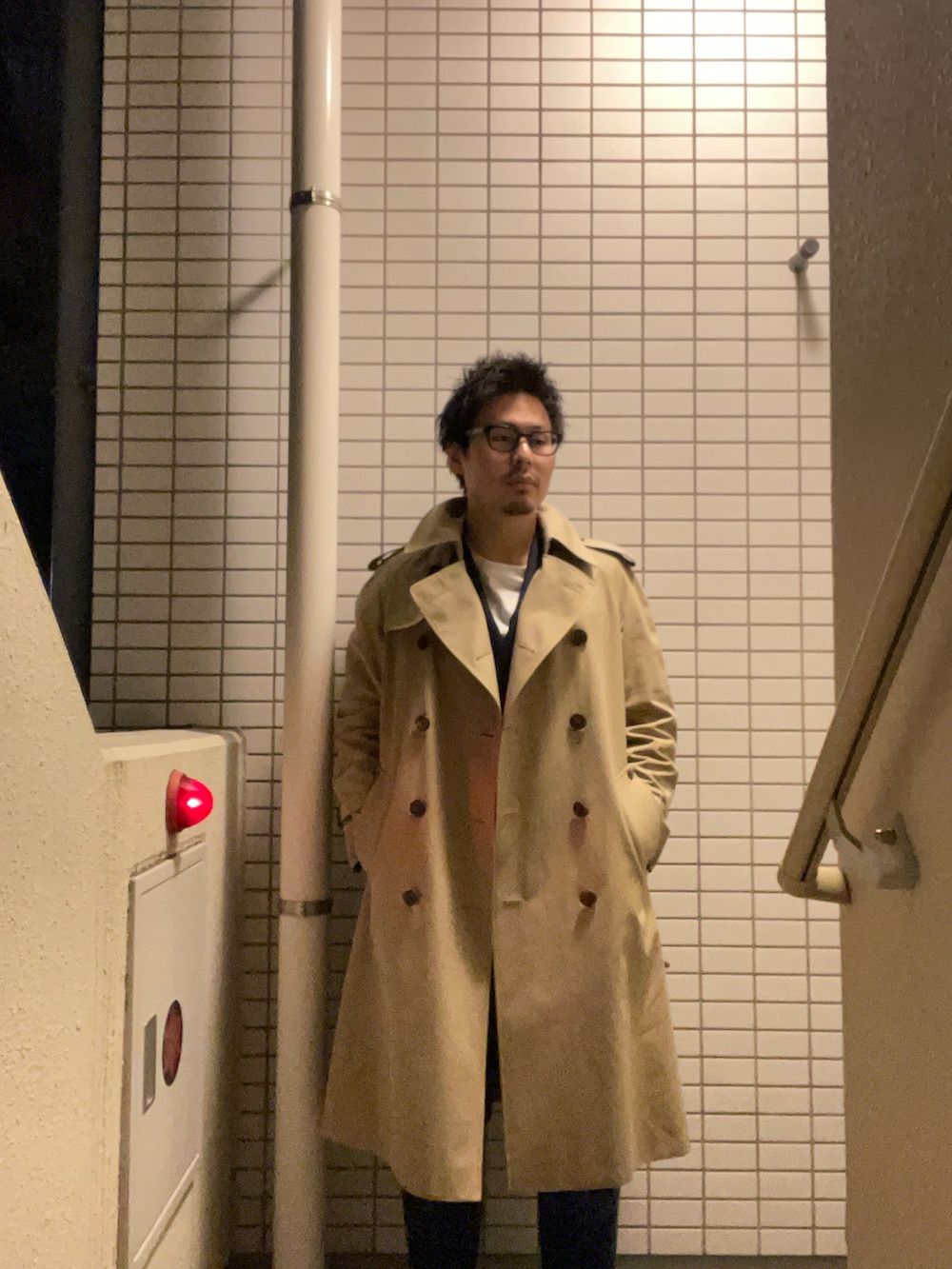 ベージュ系のトレンチコート、ブルー系のテーラードジャケット、ブルー系のデニムパンツを着用したメンズの秋コーディネートの2枚目の写真