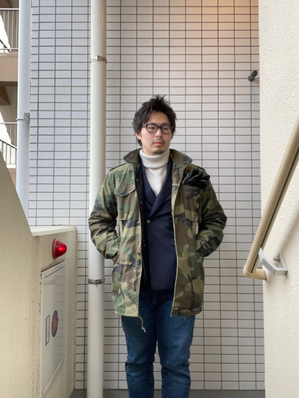 グリーン系のミリタリージャケット、ブルー系のテーラードジャケット、ベージュ系のニット/セーターを着用したメンズの冬コーディネートの2枚目の写真