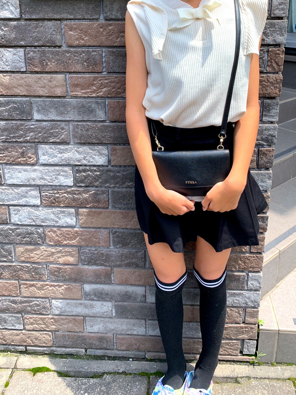 ホワイト系のTシャツ/カットソー、ブラック系のショルダーバッグ、ブラック系のスカートを着用したキッズの秋コーディネートの2枚目の写真